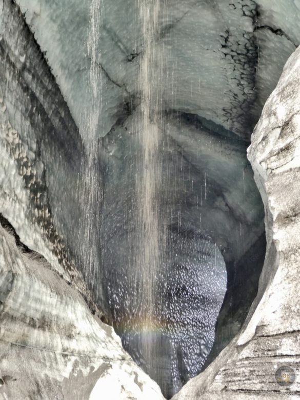 Ein Wasserfall aus Schmelzwasser am Eingang der Dragon Glass Eishöhle.