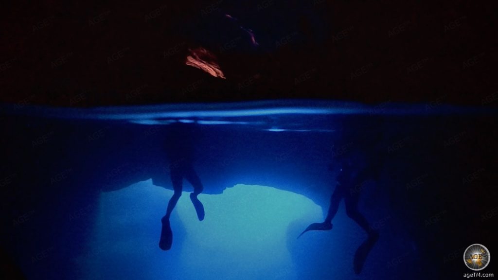 Unterwasserfoto zeigt 2 Höhlentaucher halb unter und über Wasser. Höhlentauchen in der Cathedral Cave Insel Gozo Malta. Tauchen Aktivurlaub auf den Inseln Malta Gozo Camino Europa