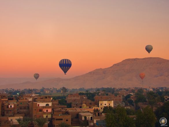 Ballonfahrt im Morgenrot über den Dächern der Stadt.