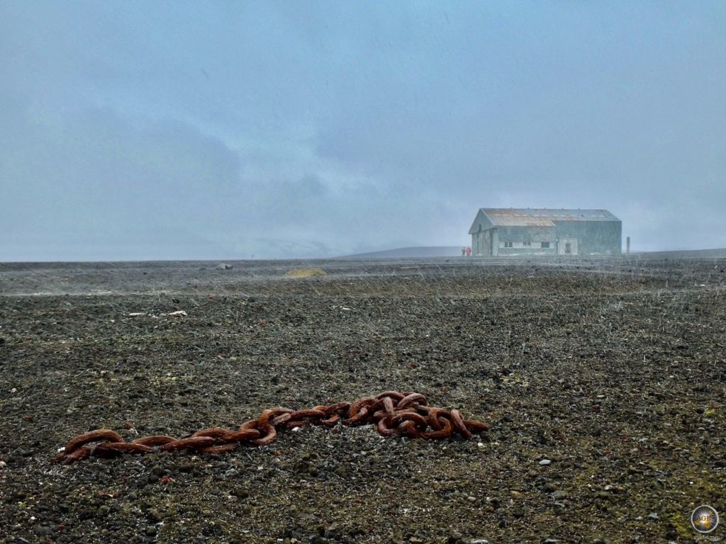 Eisenkette und Flugzeughangar auf Deception Island im Schneeregen.