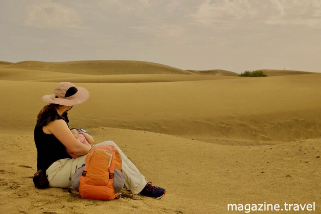 Mutter mit Baby im Arm in den Sanddünen von Maspalomas auf Gran Canaria im Urlaub